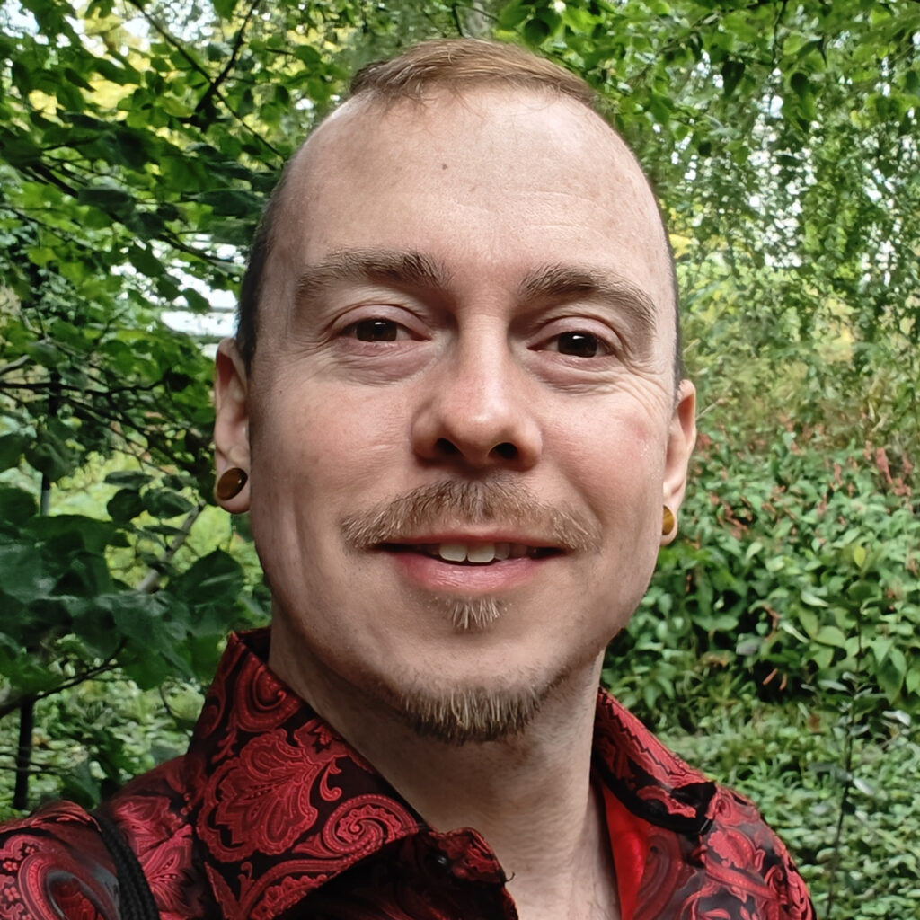 Kep wearing a red shirt with trees in the background